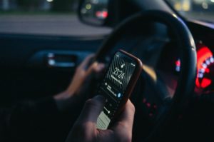 person sitting behind the steering wheel of a car with their phone in their hand