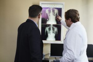 doctors looking at n x-ray of someone's spinal cord