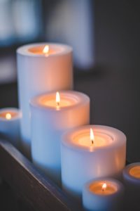 three lit white candles lined up from shortest to tallest