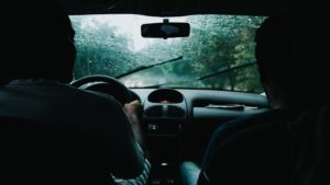two people inside a car driving in the rain