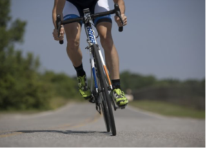 a person's legs as they bike on the road moving toward the camera