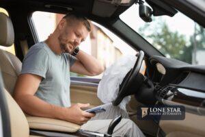 Injured man near opened airbag in automobile after car accident